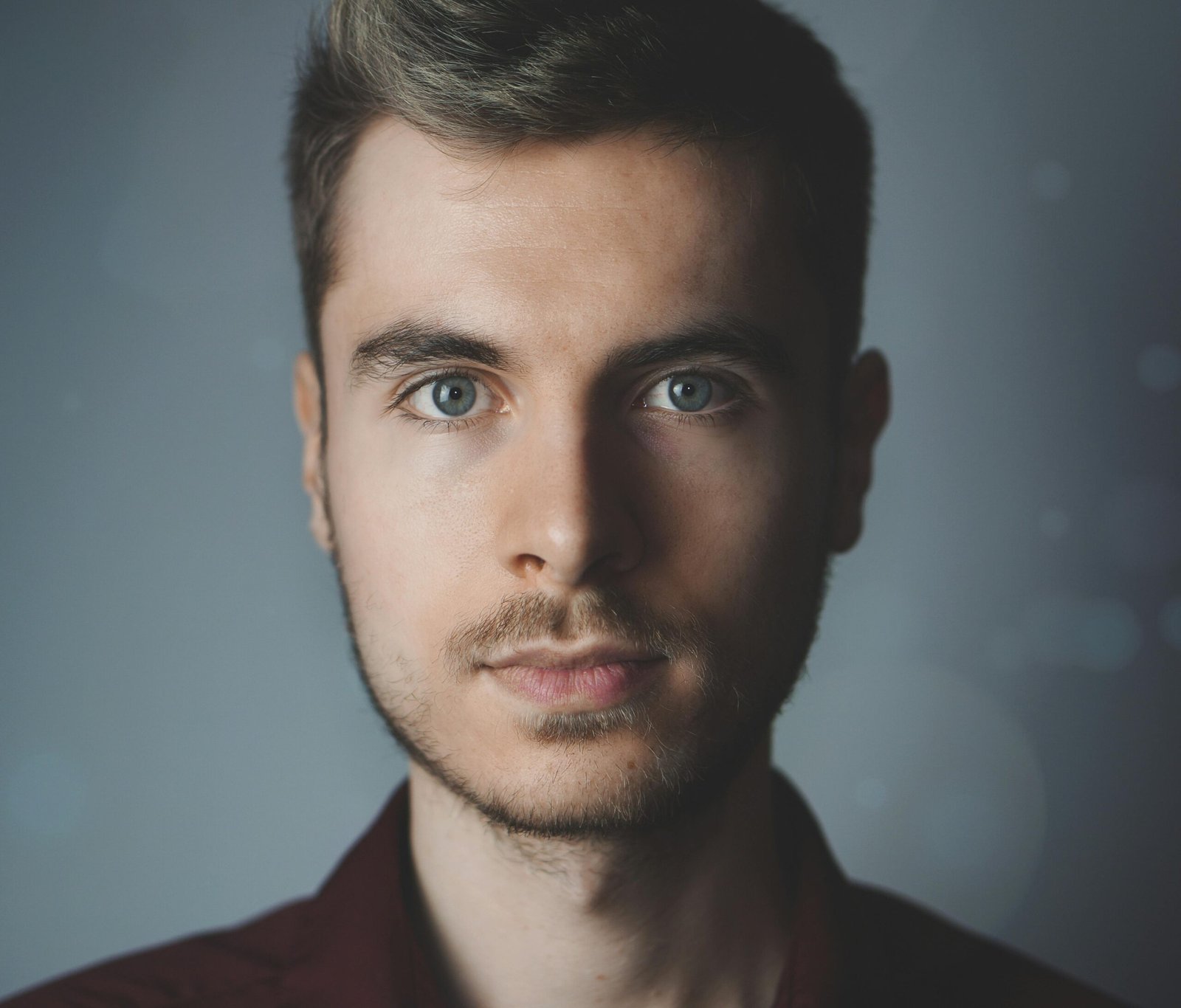 pexels-photo-614810-614810 Close-up portrait of a young man with facial hair and a serious expression.